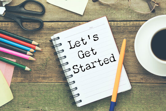 White notebook with the text LET IS GET STARTED on the table