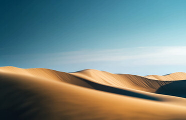 Vast desert sand dunes under a clear blue sky with natural ripples and shadows in golden sunlight
