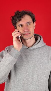 man answers phone, outraged annoying advertisements, refuses services offered, says no, becomes angry, aggressive, turns off call. Isolated red background, studio shot. concept - spam, phone surveys.