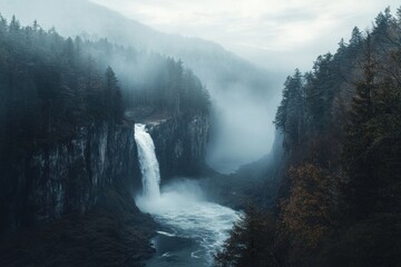 Majestic waterfall cascading down a forested mountain landscape in the mist