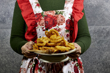 closeup woman holding a plate of Griwech crunchy pastries , an Algerian dessert made with dough, fried and then coated with syrup and sesame seeds