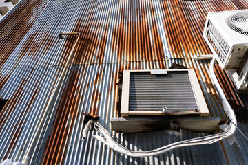 古い老朽化した建物に取り付けられたエアコンの室外機