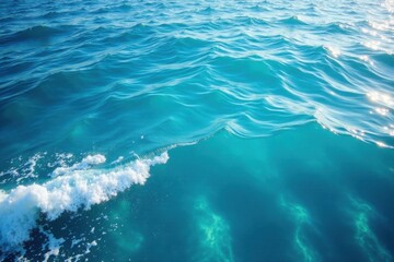 Obraz premium Wavy blue ocean surface with white foam and sunlight reflection, calming, white