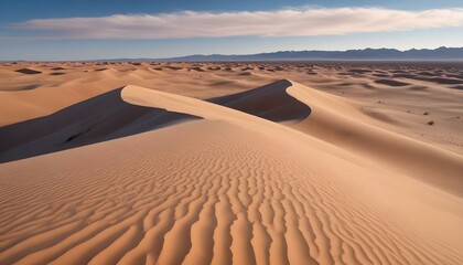 A panoramic shot captures a vast desert landscape under a clear blue sky dotted with wispy clouds