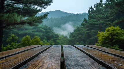 Obraz premium Wooden picnic table overlooking misty mountain forest