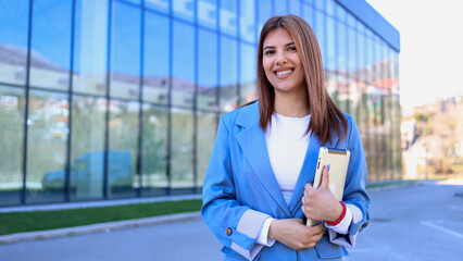 Fototapeta premium Smiling businesswoman holding tablet in front of modern office building