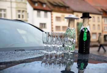 Elegant glassware and creatively dressed bottles stand out on a wet surface in an outdoor setting...