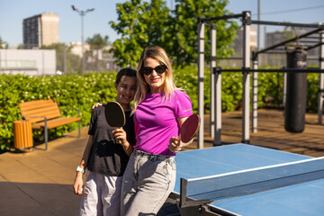 mother and daughter play ping pong in park