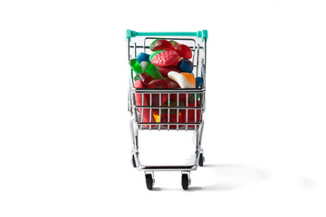 Shopping cart filled with colorful gummy candies on white background