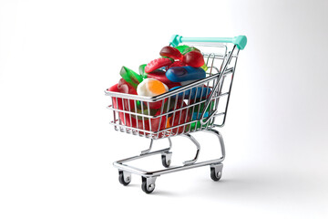 Shopping cart filled with colorful gummy candies on white background
