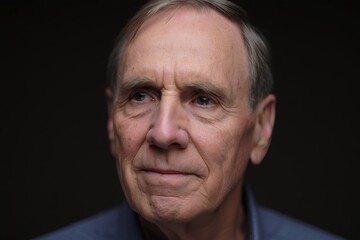 Fototapeta premium Elderly man with thoughtful expression in cozy sweater against dark backdrop showing a glimpse of wisdom and serenity