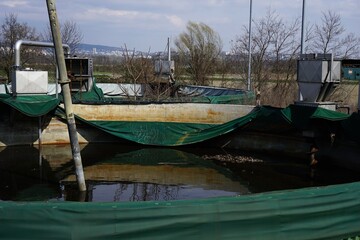 Abandoned biogas plant with a large circular wastewater tank, conveyor belt, and metal bunkers,...