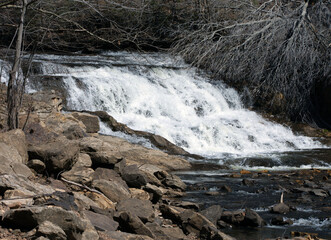 A waterfall with large boulders in the foreground.
