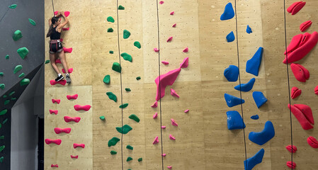 Teenage girl at indoor climbing wall. Kid having fun at bouldering wall. Child learning at climbing class. Sports healthy lifestyle. Youth at climbing summer camp