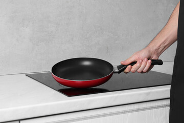 Chef holding frying pan over cooktop in kitchen, closeup