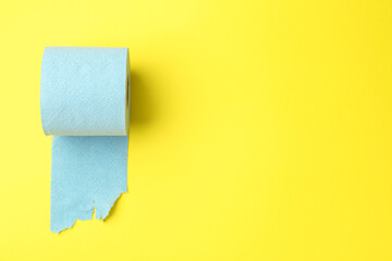 Light blue toilet paper roll on yellow background, top view. Space for text