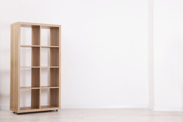 Empty wooden shelving unit near white wall indoors, space for text