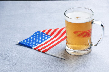Mug of beer and flag of USA on grey table