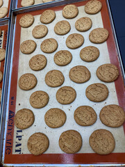 Bakers arrange dozens of perfectly shaped cookies on trays to cool in a bustling bakery environment