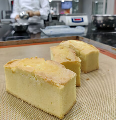 Soft, moist slices of pound cake are arranged neatly next to a whole cake, showcasing their texture and color in the bakery