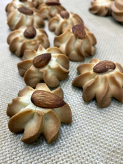 Swirl cookies made from rich dough and topped with nuts are laid out on a baking sheet, ready for...