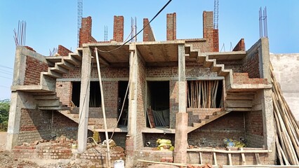 Obraz premium Workers are seen on a construction site where walls are taking shape with exposed bricks and scaffolding in bright daylight