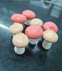 Colorful mushroom-shaped bakery products arranged creatively on a dark countertop, showcasing unique designs and textures