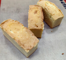 Soft, moist slices of pound cake are arranged neatly next to a whole cake, showcasing their texture and color in the bakery
