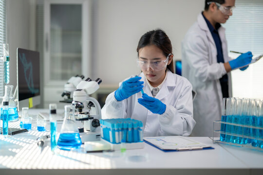 A woman in a lab coat is holding a test tube