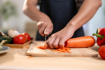 A person is cutting a carrot on a wooden cutting board