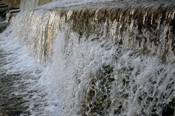 A close-up view of a fast flowing stream over the edge of an escarpment forming a waterfall.