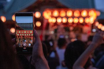 hand holding smart phone to record summer bon odori festival in kanda myoujin shinto shrine at night