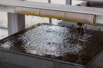 water flowing out from bamboo at water purification place called chozuya in matsudo shrine