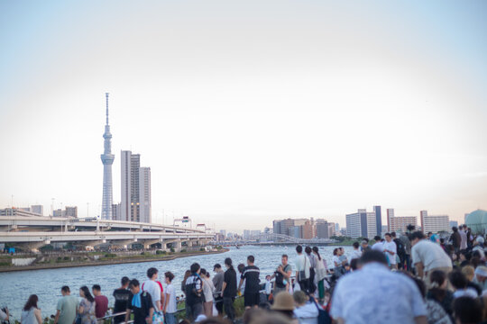 scenery with tokyo sky tree and a lot of people gathering at riverside of shioiri park to view sumida river fireworks festival 2023 before sunset in minami-senju, arakawa city