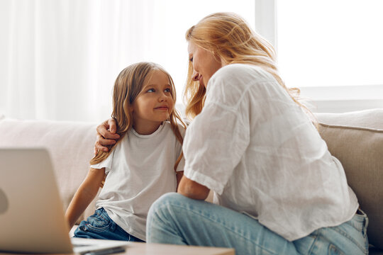 Loving mother and daughter enjoying quality time together, using a laptop at home