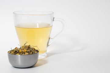 Cup of chamomile tea with loose chamomile tea in a bowl. Isolated against white with copy space.