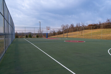 Basketball court in an outdoor park under cloudy evening sky