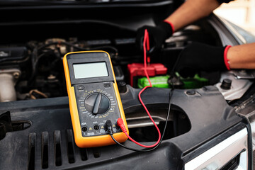 Voltmeter and Technician car mechanic to check electrical voltage battery low energy problem for...