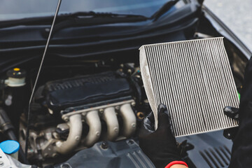 Car care maintenance servicing technician or auto mechanic holding car air conditioner filter for...