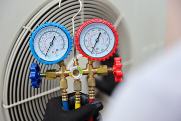 Electrical technician conditioning using manifold gauge measuring tool checking refrigerant pump...