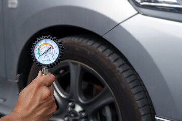 Hand car mechanic holding car tire pressure check equipment tool to checking low tire pressure...