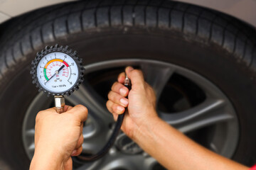 Hand car mechanic holding car tire pressure check equipment tool to checking low tire pressure...