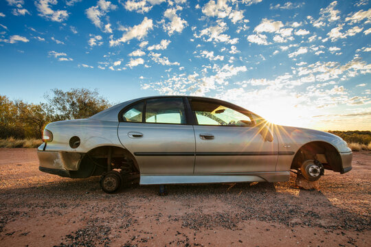 An abandoned sedan without wheels sits besides the Stuart Highway in Central Australia