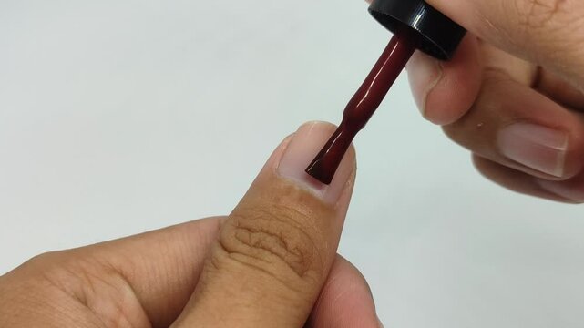 Apply nail polish on the thumb of the left hand with a white background