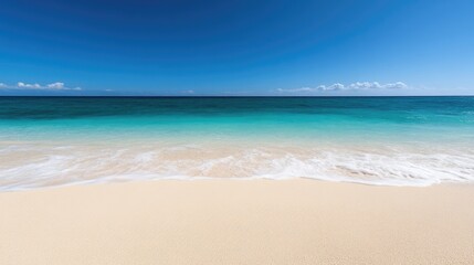 Obraz premium Pristine beach scene with turquoise ocean and a clear blue sky. Soft waves gently caress the golden sand