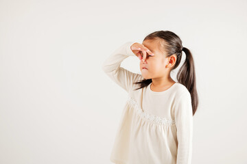 Asian young child unhappy what smell disgust expression squeezing nose with fingers. Kid girl...