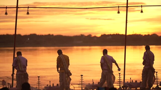 Hindu priests perform the Ganga Aarti ritual in Varanasi, holding large multi-tiered oil lamps in a synchronized spiritual ceremony.