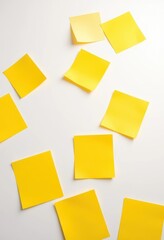 Several vibrant yellow paper notes scattered on clean white surface, ample empty space, white background, bright