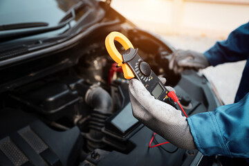 Close-up hand auto mechanic using meter to check car battery fail problem for service or change...