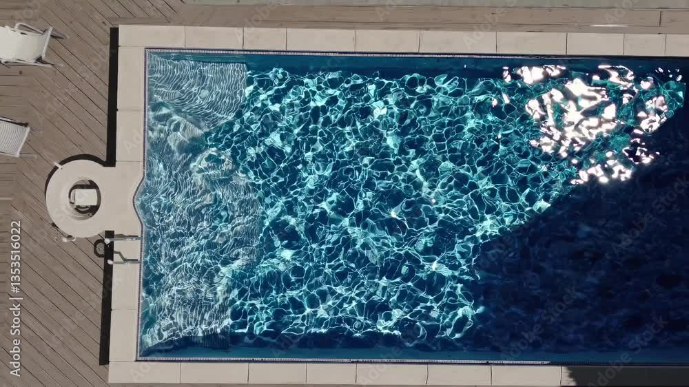 Poster top-down video of a swimming pool with sunlight creating shimmering patterns on the water, capturing